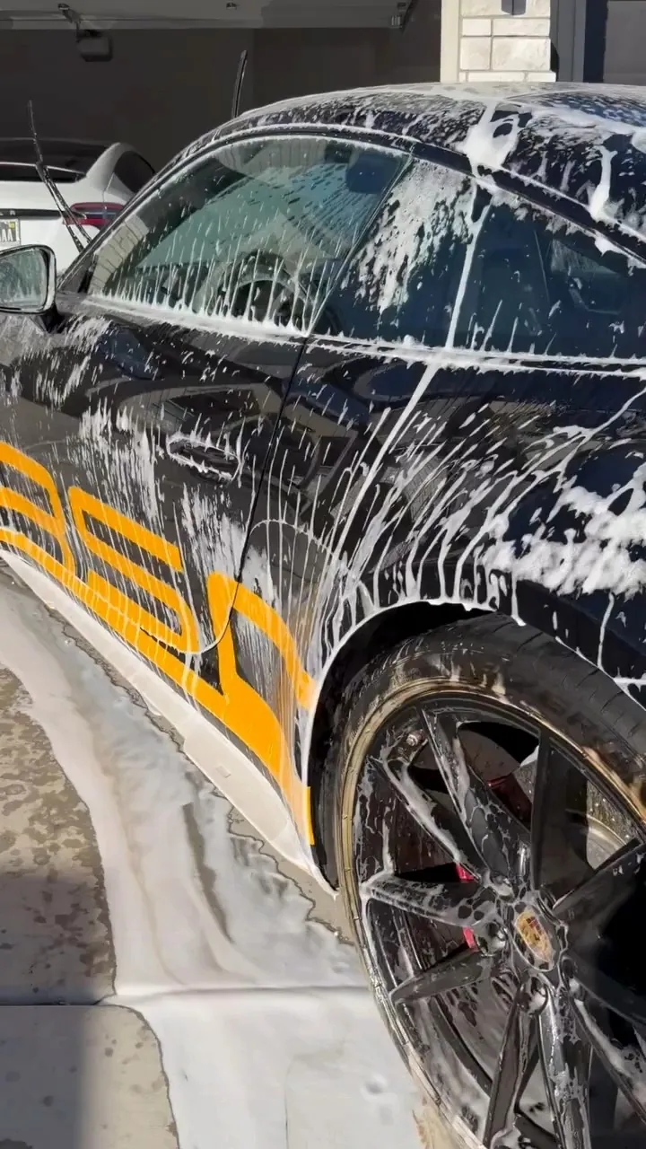 Soap-covered black and orange Porsche during a hand wash